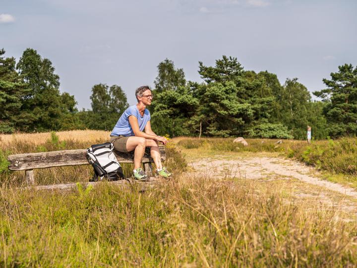 Urlaubsgast macht Pause während einer Wanderung in der Lüneburger Heide.