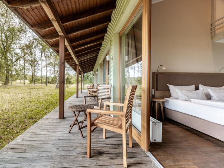 Ebenerdiges Hotelzimmer mit Holzterrasse und Gartenmöbel
