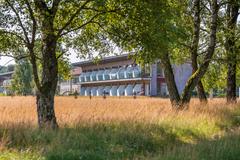 Wiese mit Gräsern und Birken und Blick auf einen Zimmertrakt eines Hotels