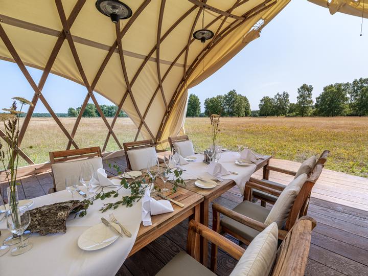 Großes Zelt mit eleganter Holzkonstruktion und Aussicht nach draußen, mit festlich gedecktem Tisch